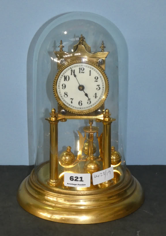 A gold anniversary clock with a white clock face and black numbers, encased in a glass dome on a gold base.